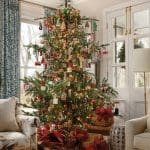 Living room with Christmas tree, patterned armchair, and French doors.