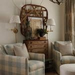 Living room with plaid armchairs, wooden dresser, and wall sconces.