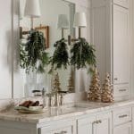 White bathroom vanity with marble countertop, silver faucets, and pine boughs.