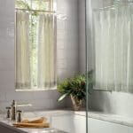 White bathroom with subway tile, marble countertop, and patterned curtains.