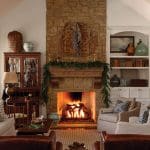 Living room with stone fireplace, lit fire, and built-in bookshelves.