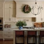 Cream kitchen with wreath, chandelier, and blue and white vase with greenery