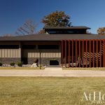 Modern home with stone and tan siding, featuring a slatted wood entryway and large windows.