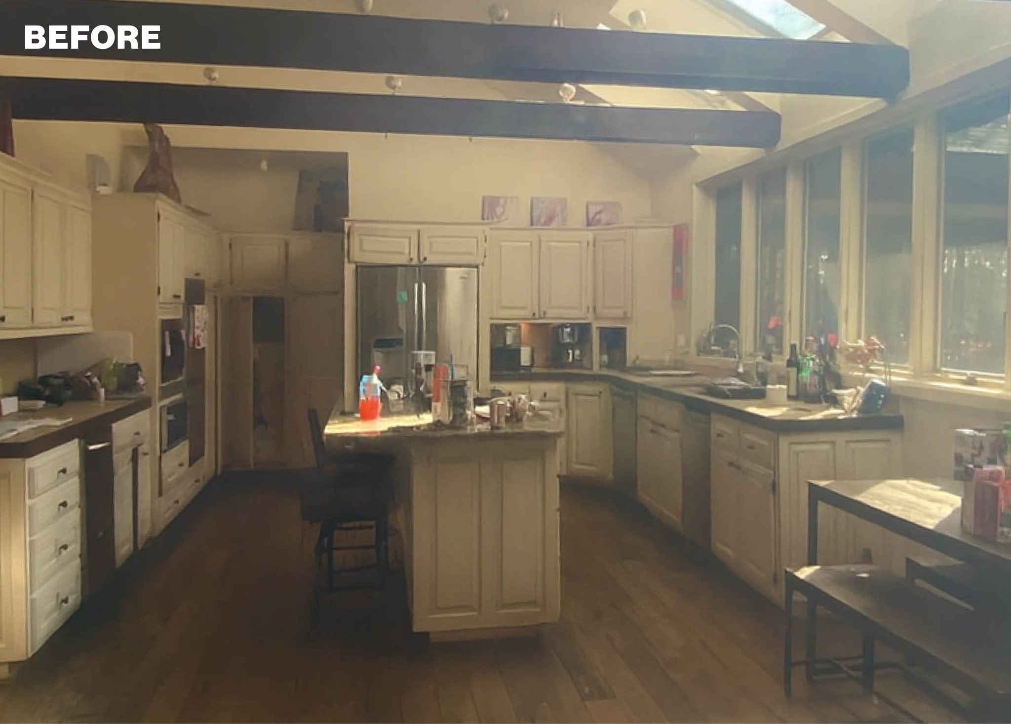Kitchen with cream cabinets, granite island, stainless steel appliances, and wood floors.