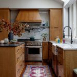 Oak cabinetry, marble backsplash, and stainless steel range in a modern kitchen.