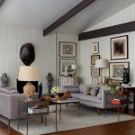 Living room with gray sofas, slatted walls, beamed ceiling, and artwork.