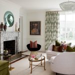Living room with marble fireplace, patterned curtains, and upholstered sofas.
