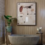 Bathroom with concrete tub, wood slat walls, and abstract art