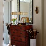 Wooden dresser with ornate mirror, lamp, and collection of canes.