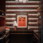 Kitchen with striped marble backsplash, black cabinets, and abstract art