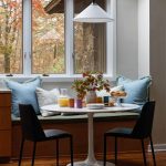 Breakfast nook with banquette seating, tulip table, and fall foliage view.