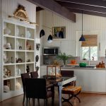 Dining area with mirrored table, upholstered chairs, and open shelving filled with decor.