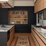 Modern kitchen with black cabinetry, wood accents, marble countertops, and a patterned runner.