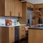 Kitchen with light wood cabinets, marble backsplash, stainless steel refrigerator, and dark