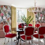 Dining room with floral wallpaper, red upholstered chairs, and a wooden table.