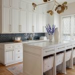 White laundry room with custom cabinetry, navy subway tile backsplash, and marble island with