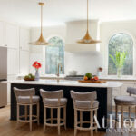 Kitchen with white cabinets, dark island, and four patterned bar stools.