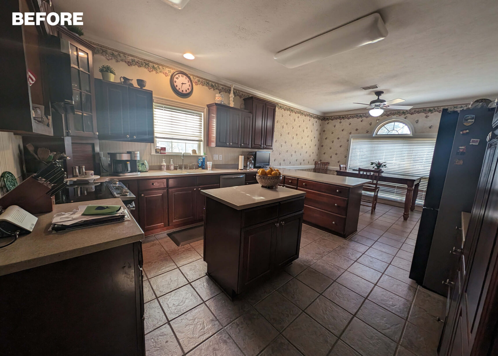 Dark wood kitchen with two islands, beige countertops, and tiled floor.