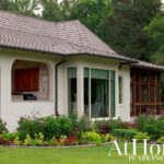 Luxury home with cedar shake roof, white stucco walls, stone accents, and screened porch.