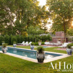 Rectangular pool with lounge chairs and brick fireplace in backyard