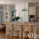 Kitchen island with rattan stools, blue banquette seating, and pendant lights.