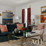 Living room with dark green sofa, patterned pillows, and brass coffee table.