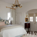 Bedroom with blue upholstered headboard, floral pillows, and white quilted bedding.
