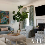 Living room with blue sofa, patterned chairs, fiddle leaf fig tree, and fireplace.