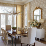 Dining room with ornate chandelier, patterned wallpaper, and a large wooden table.