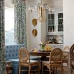Dining room with blue tufted banquette, rattan chairs, and floral curtains.