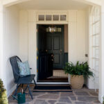 Dark green Dutch door open to entryway with patterned tile floor. Bench with pillow.