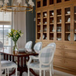 Dining room with light blue checkered chairs, dark wood table, and large oak china cabinet.