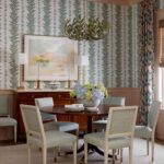 Dining room with green leaf wallpaper, round table, and upholstered chairs.