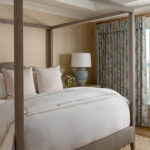 Bedroom with a four-poster bed, white bedding, leopard print pillows, and floral curtains.