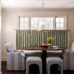 Dining room with striped chairs, patterned ottomans, round table, and floral curtains.