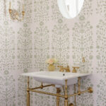 Powder room with floral wallpaper, brass fixtures, and a pedestal sink.