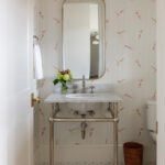 Powder room with striped wallpaper featuring swimmers, marble vanity, and hexagonal floor tiles.