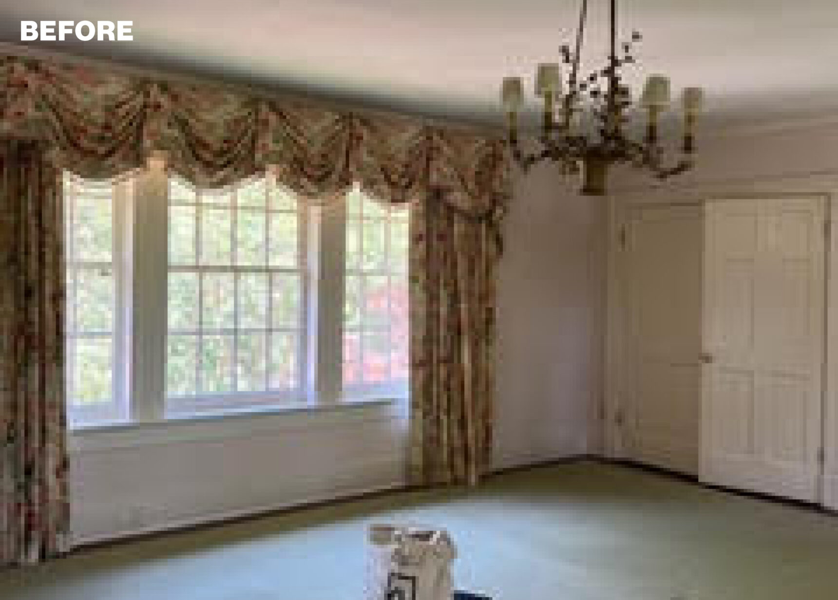Room with floral curtains, green carpet, and a chandelier.