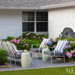 White brick house exterior with outdoor seating area and blooming hydrangeas.