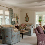 Living room with patterned sofas, lamps, and window treatments.