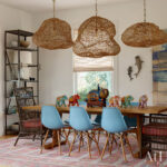 Dining room with wooden table, blue chairs, wicker chairs, woven pendant lights, and elephant