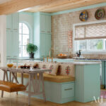 Mint green kitchen with marble island, built-in banquette, and wood ceiling
