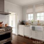 White kitchen with subway tile backsplash, stainless steel range, and farmhouse sink.