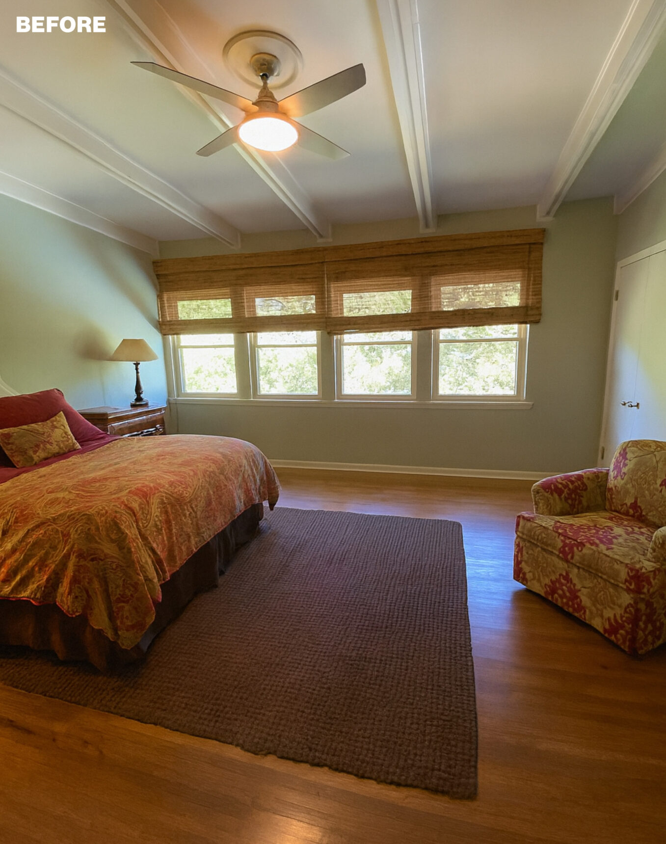 Bedroom with beige walls, rattan blinds, and a patterned rug.