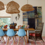 Dining room with light blue chairs, wooden table, woven pendant lights, and colorful elephant
