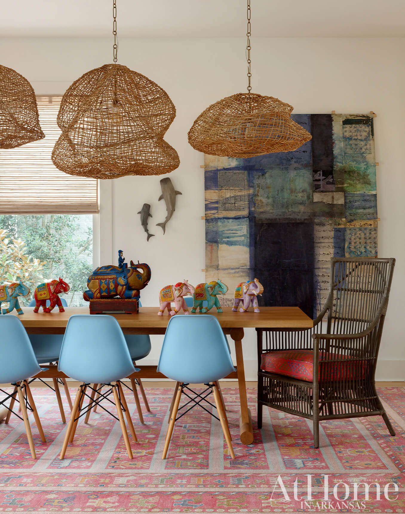 Dining room with light blue chairs, wooden table, woven pendant lights, and colorful elephant