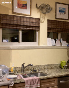 Kitchen sink with granite countertop, bamboo blinds, and framed art.