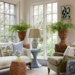 Living room with light blue side table, wicker planters, and floral pillows.
