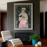 Living room with dark stone fireplace, modern art, and cream leather chairs.