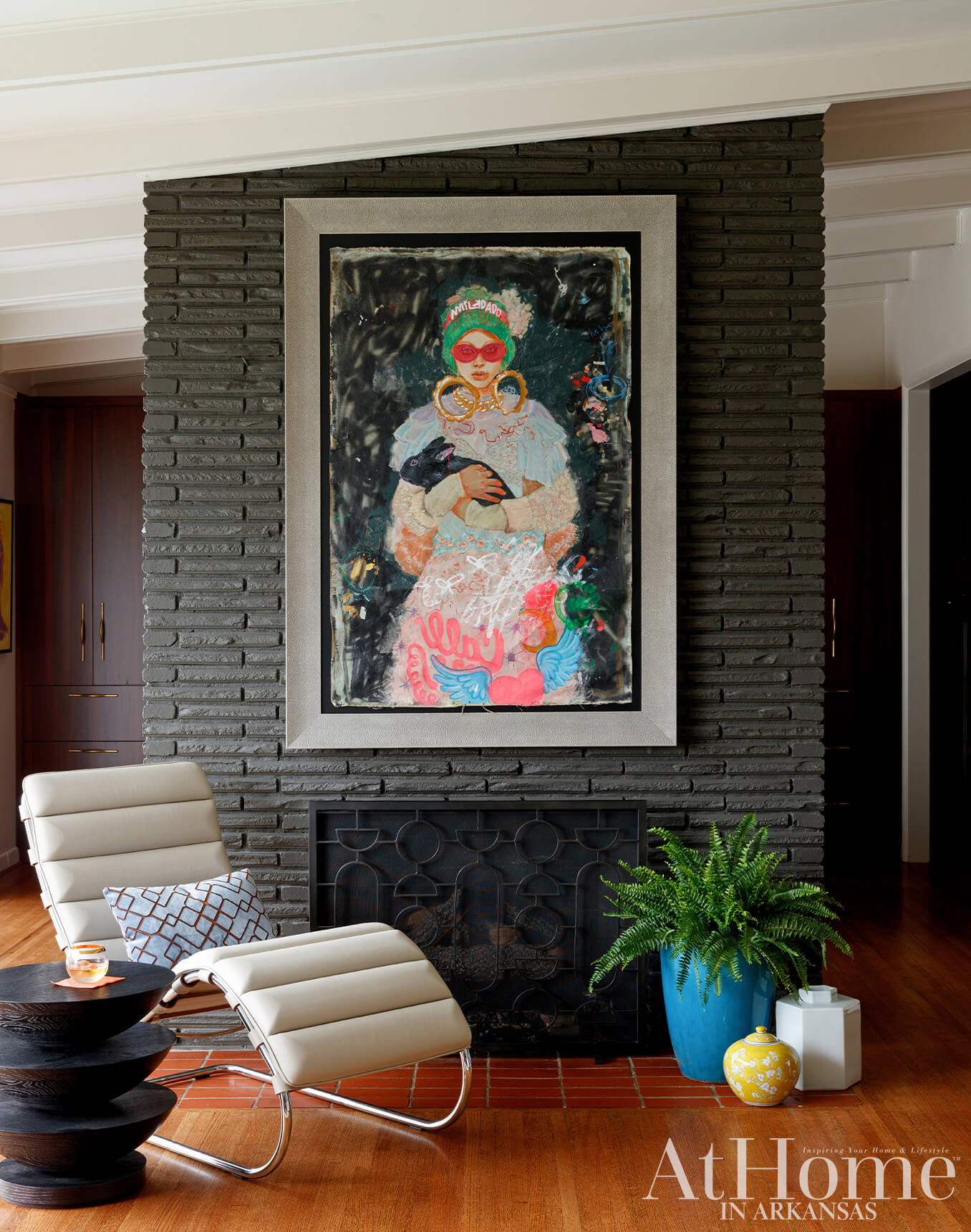Living room with dark stone fireplace, modern art, and cream leather chairs.